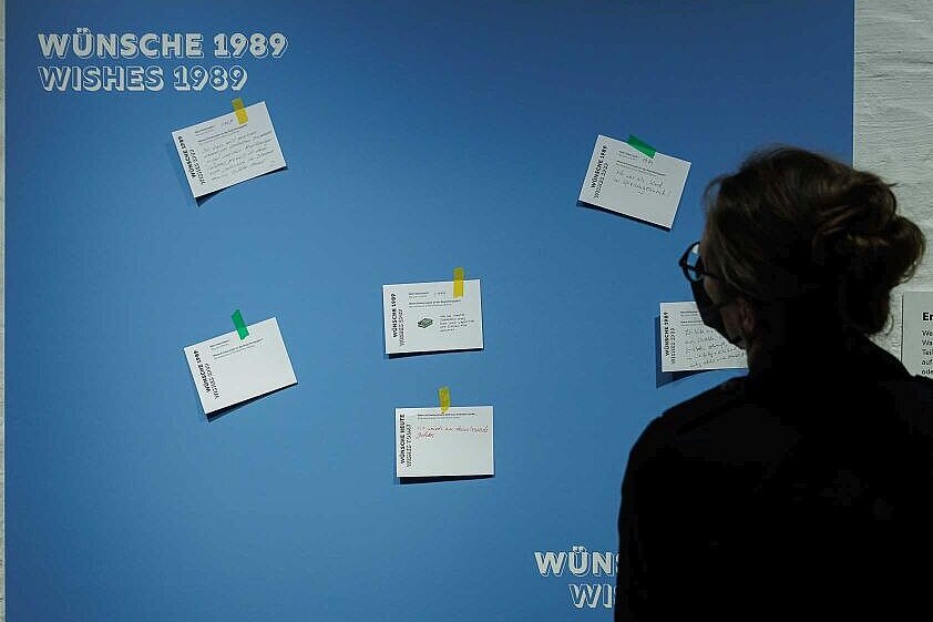 Was wünschen sich Menschen 1989? Was heute? Besucherin vor Tafel mit Wünschen in der Ausstellung