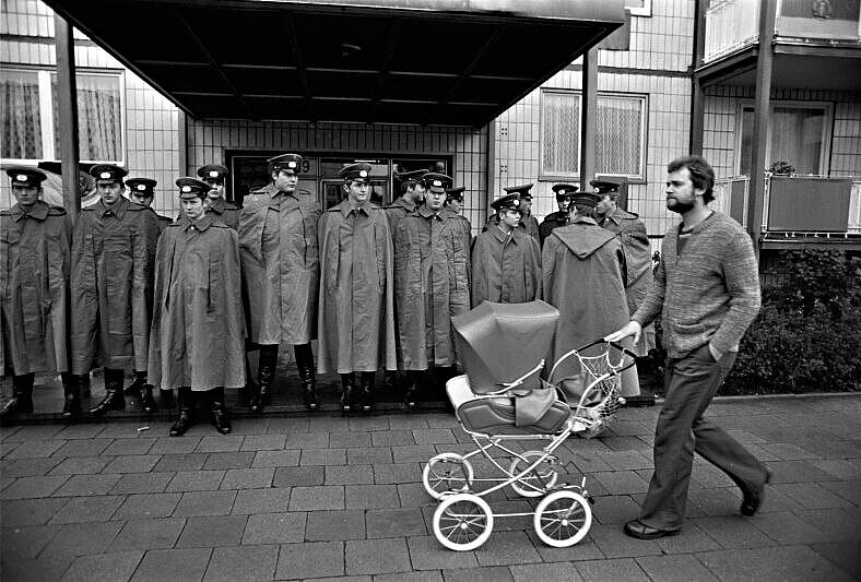 Fotografie 'Mann mit Kinderwagen vor Volkspolizisten' Fotografie 'Mann mit Kinderwagen vor Volkspolizisten'