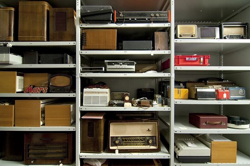 Blick auf unsere Radiosammlung im Museumsdepot Radios verschiedener Größen und Materialien stehen in einem Metallregal.