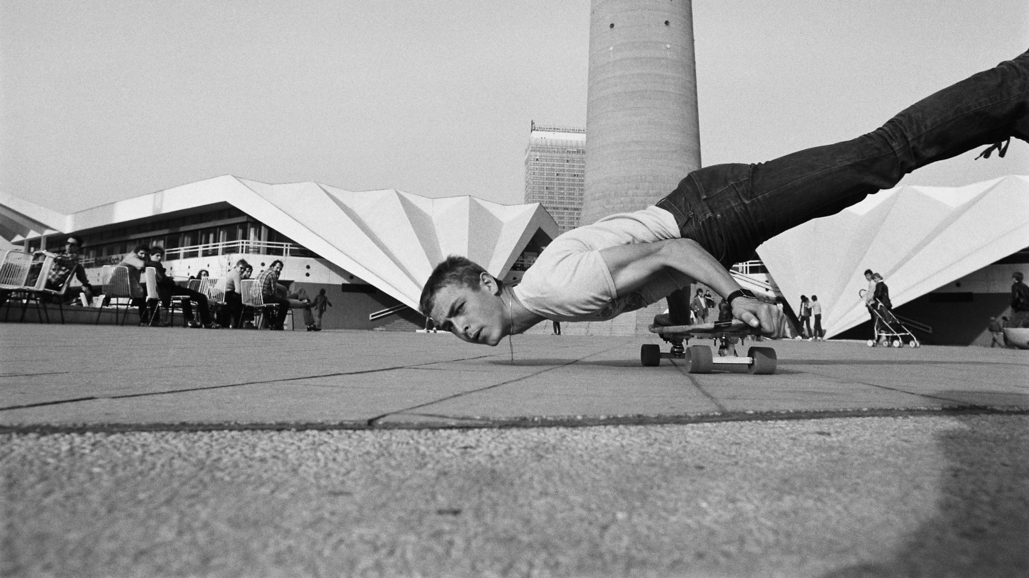 Ein Skater fährt mit den Händen auf einem Skateboard abgestützt über den Alexanderplatz.