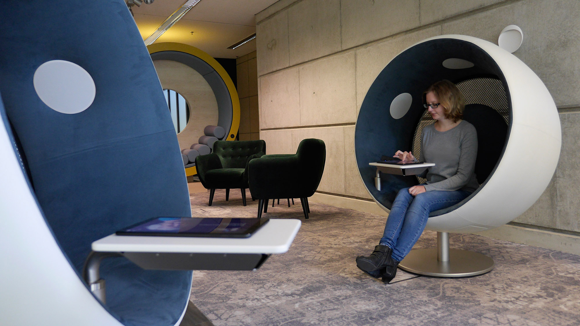 Eine Besucherin sitzt im Soundsessel mit Tablet in der Lounge Eine Besucherin sitzt in einem Sessel mit einem Tablet in der Lounge