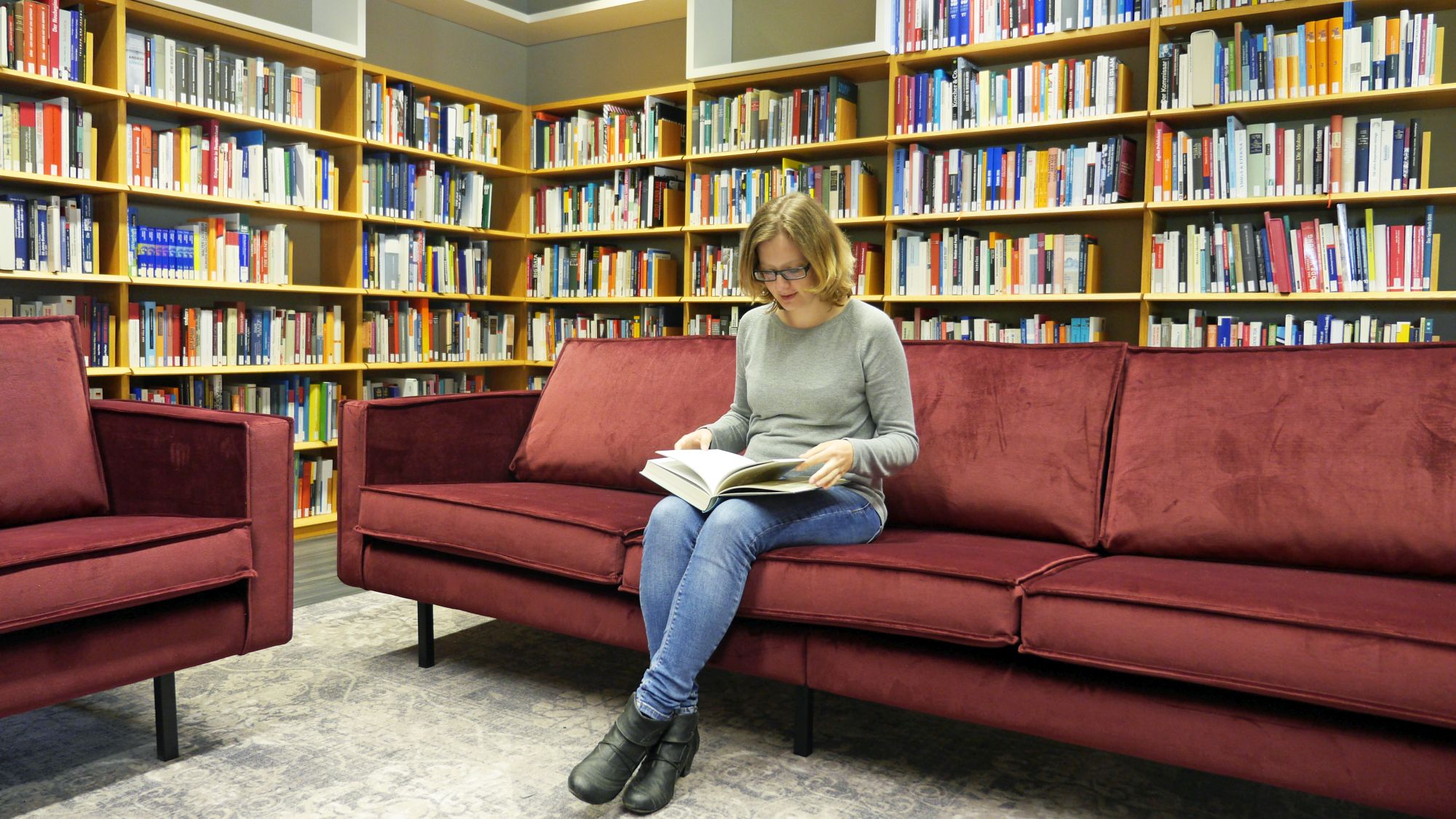 Eien Besucherin sitzt auf einem gemütlichen Sofa und liest Eine Besucherin sitzt auf einem gemütlichen Sofa und liest